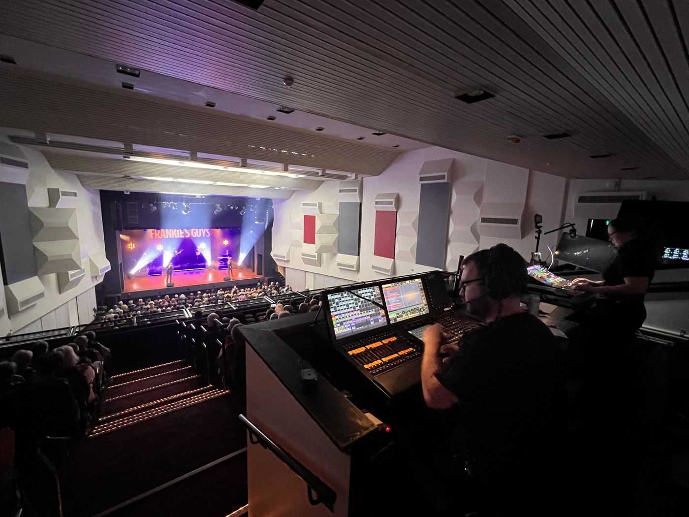 Engineers mixing a touring show from the balcony, full house below