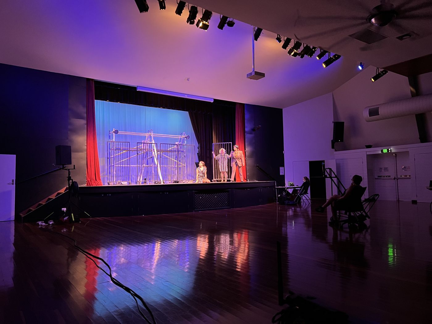 Community theatre performance in a hall, stage lit in purple